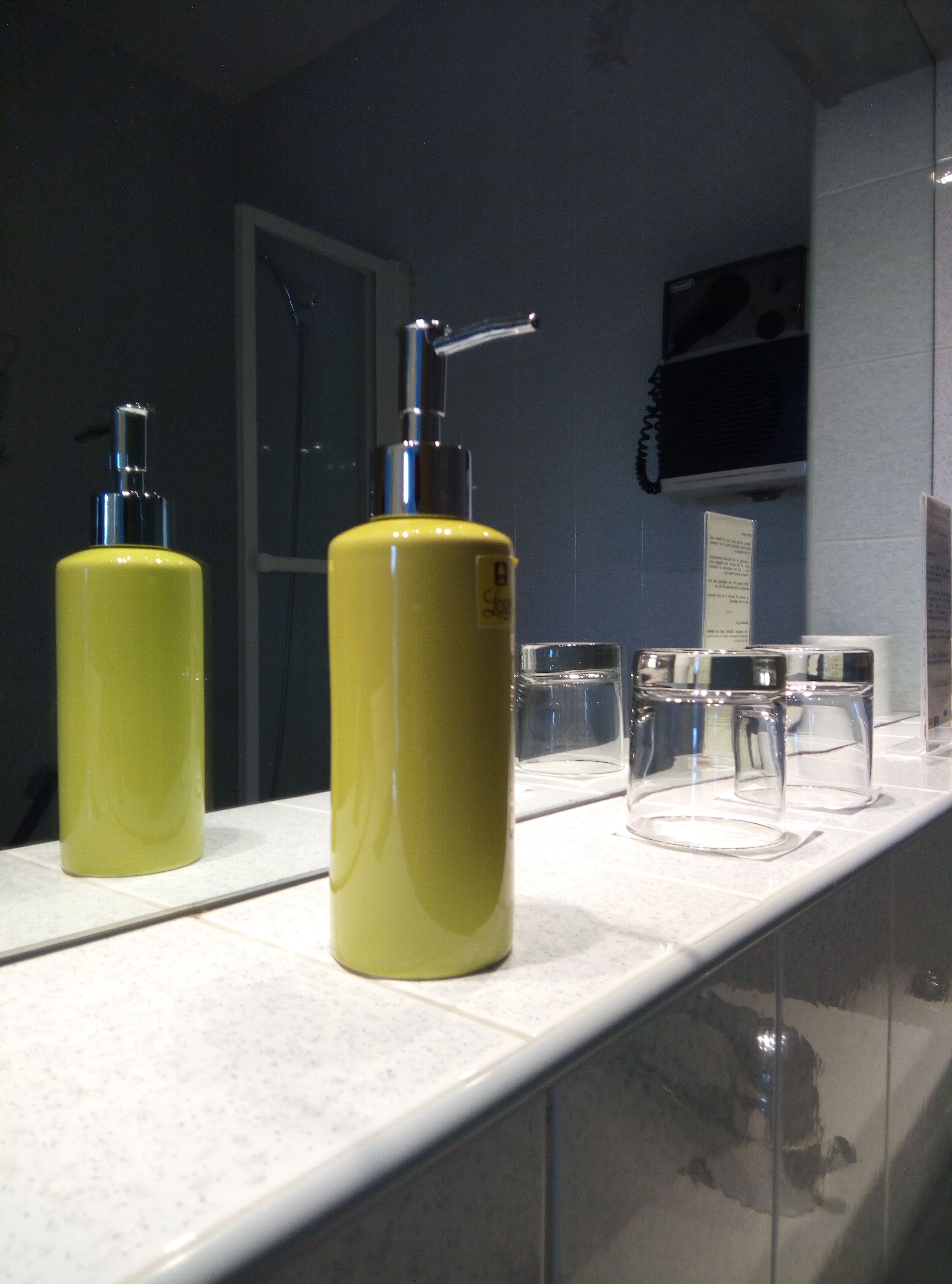 A bathroom with two yellow dispensers, a mirror, and a sink.