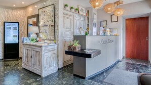 A reception desk with a wooden cabinet, a mirror, and a wall-mounted information board. - Logis Hôtel la Maison Carrée (Mereville)