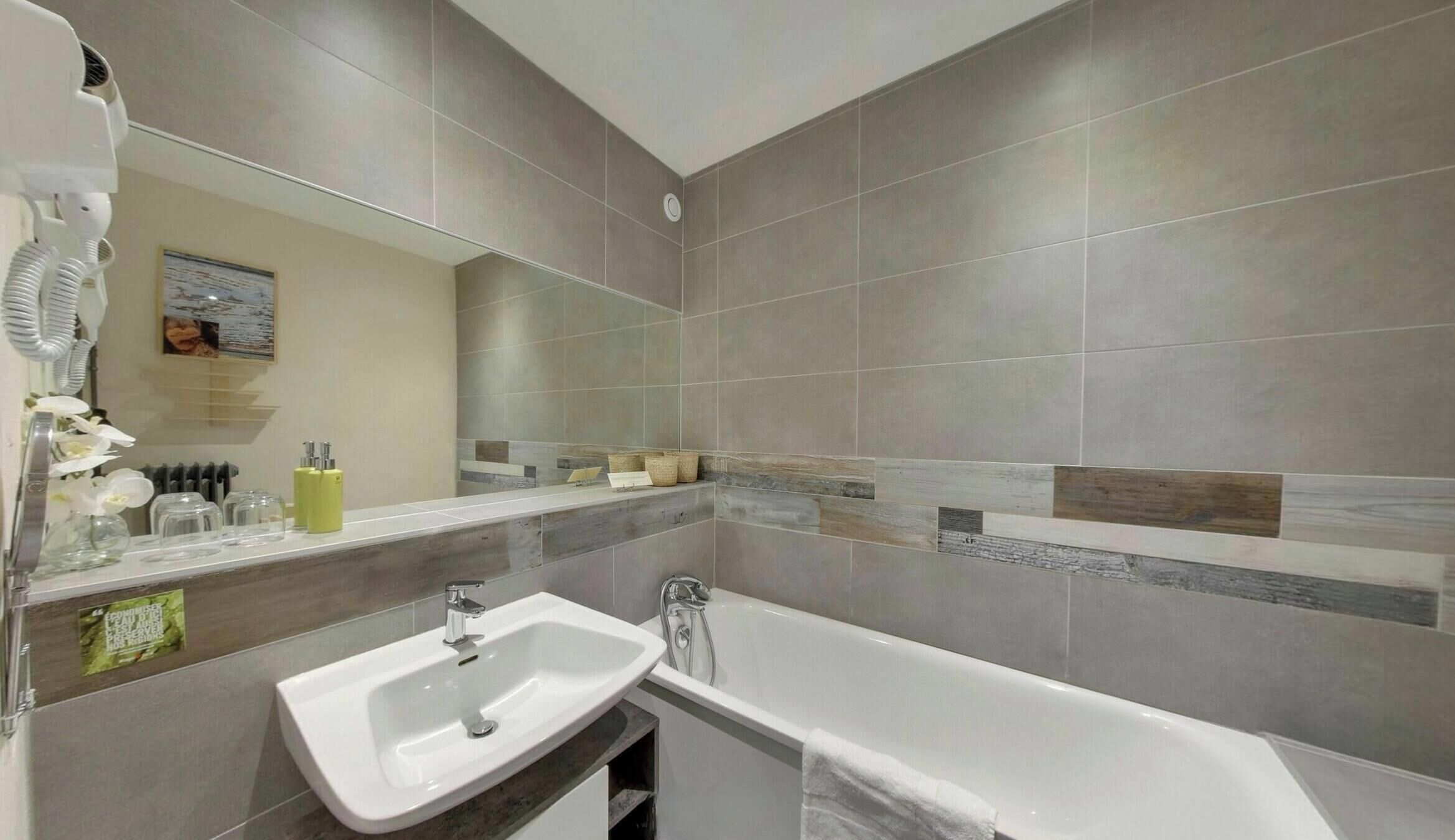 A modern bathroom with a bathtub, sink, and mirror.