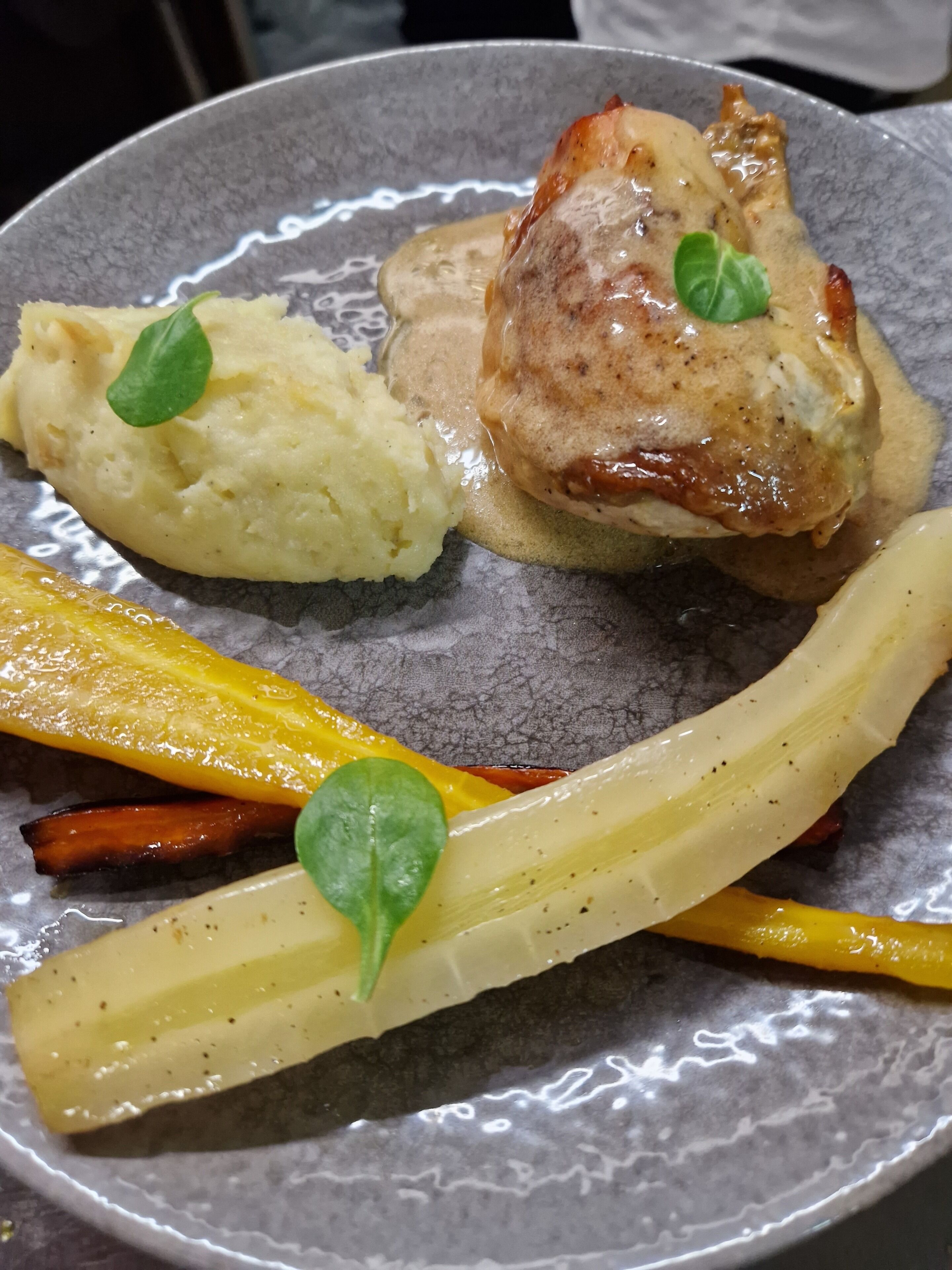 A plate with a piece of meat, mashed potatoes, and vegetables.