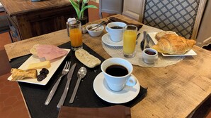 A breakfast table with croissants, ham, bread, coffee, and juice. - Logis Hôtel la Maison Carrée (Mereville)