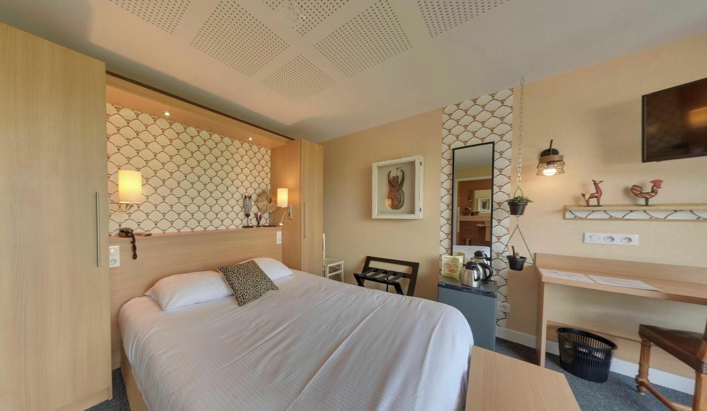 Une chambre d’hôtel comprenant un lit, une table de chevet, un bureau, une chaise et un miroir.