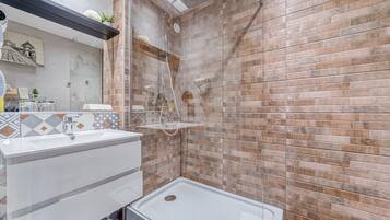 A bathroom with a shower, a sink, and a mirror.