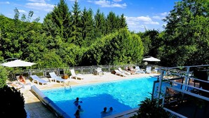 A swimming pool with lounge chairs and umbrellas, surrounded by trees. - Logis Hôtel la Maison Carrée (Mereville)