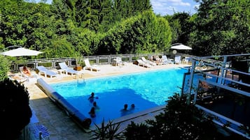 Una piscina al aire libre, sillones reclinables de piscina