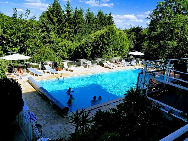 Una piscina al aire libre, sillones reclinables de piscina