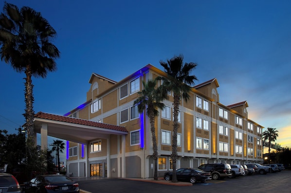A multi-story hotel with a covered entrance and a parking lot.