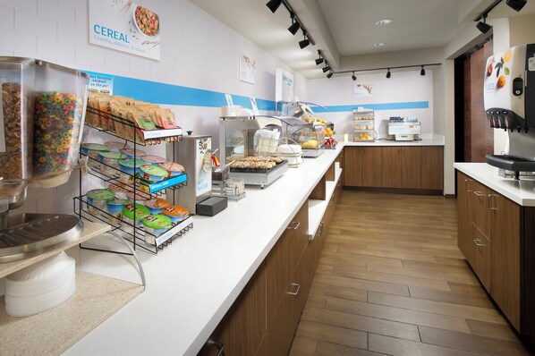 A breakfast buffet area with various food options like cereal, oatmeal, and hot water.