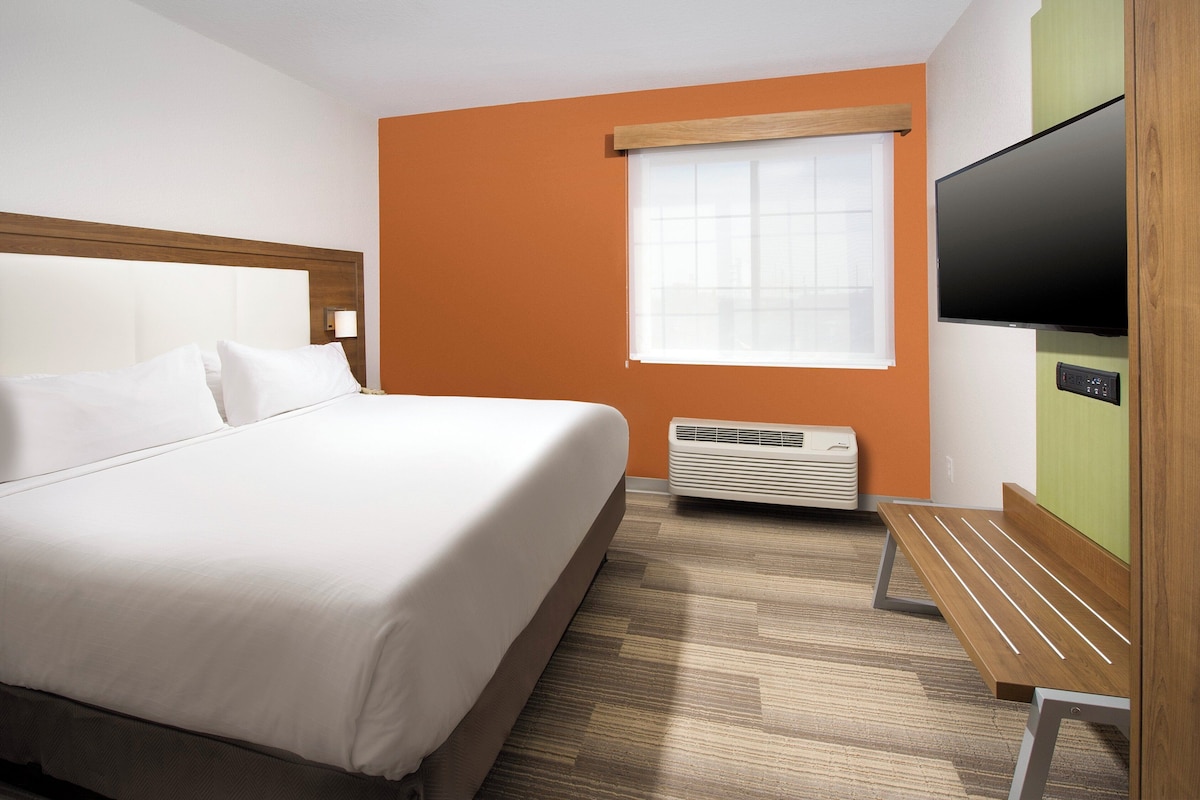Quarto de hotel com cama, televisão, aquecedor e janela.