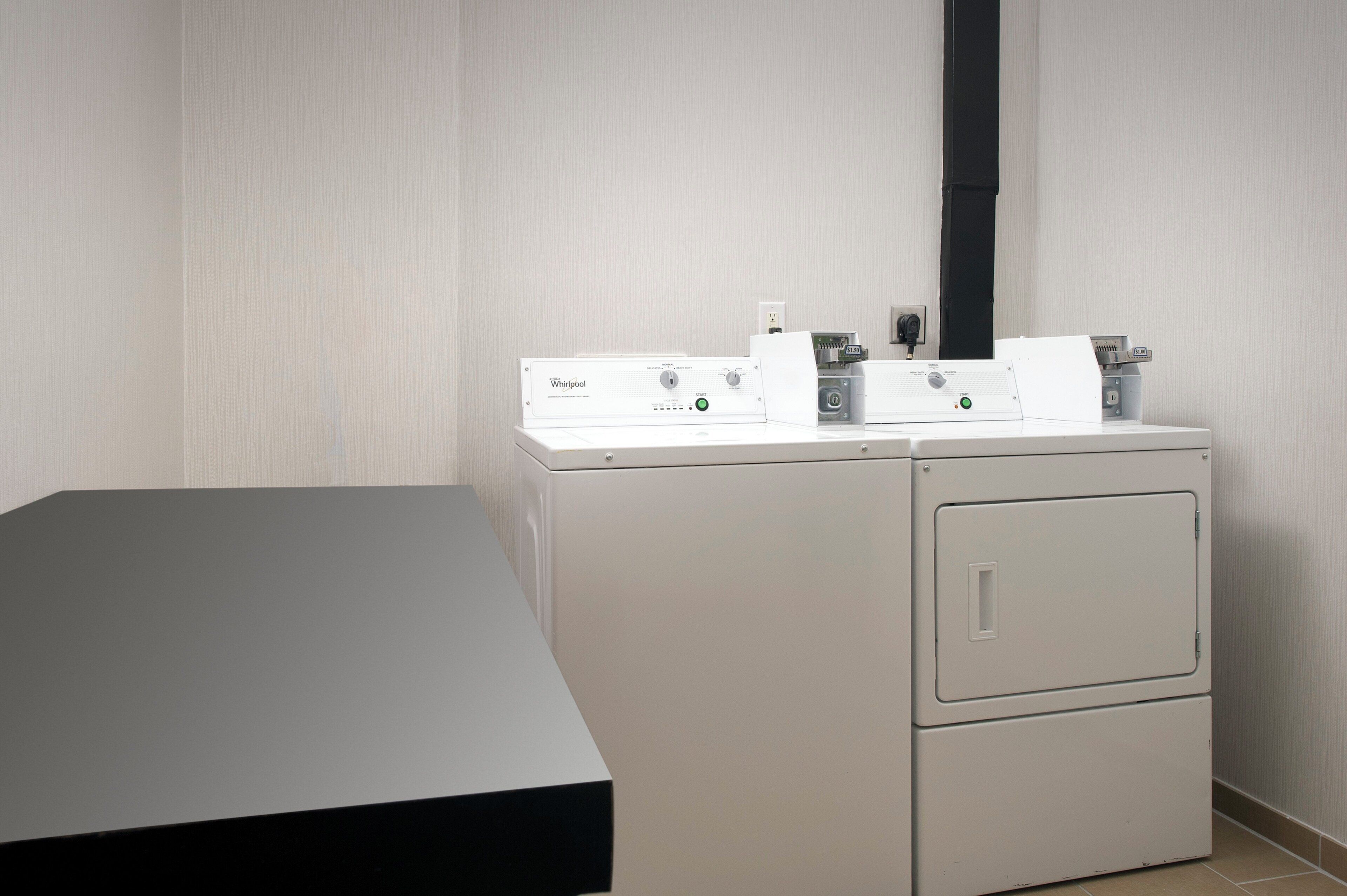 A laundry room with a washing machine and dryer, a power outlet, and a control panel.