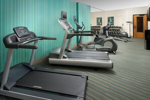 A fitness center with treadmills, elliptical machines, and a wall-mounted TV.