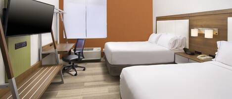 A hotel room with two beds, a TV, a desk with a chair, a window with blinds, and a bedside table with a lamp.