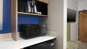 Una kitchenette equipada con microondas, cafetera y un refrigerador pequeño.