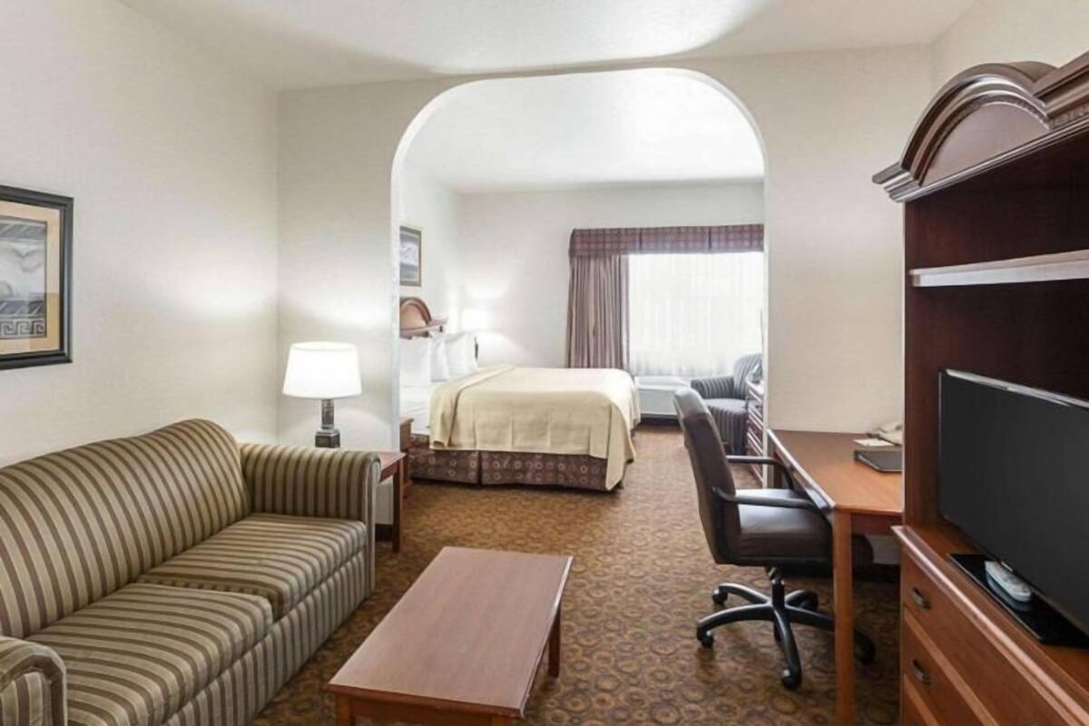 Een hotelkamer met een bank, een bed, een bureau, een televisie en een kamer met een patroon.