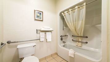 A bathroom with a toilet, a bathtub with a shower curtain, a grab bar, and a small shelf with towels.