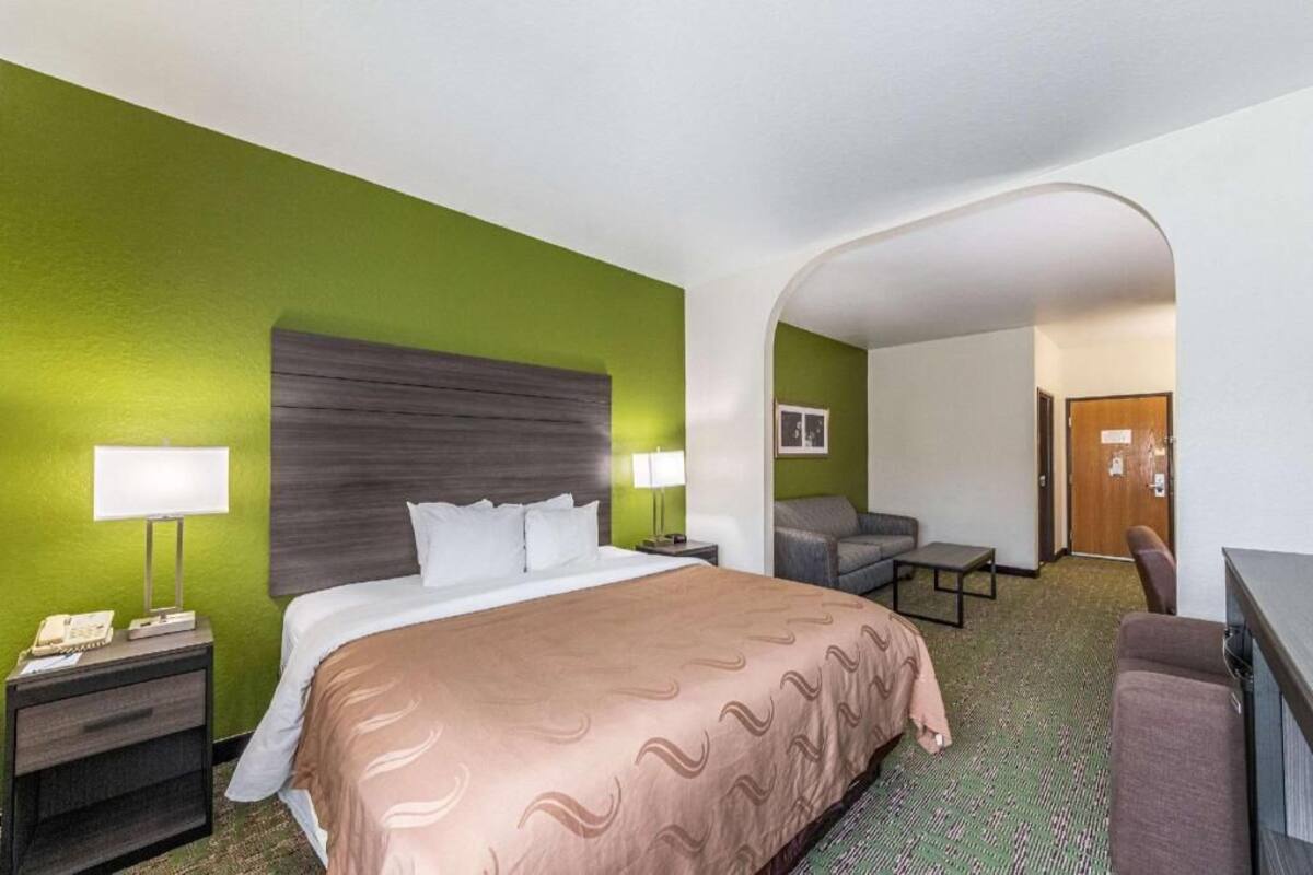 Een hotelkamer met een bed, een bureau, een stoel en een klein tafeltje.