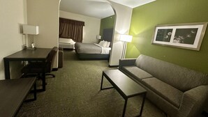 Een hotelkamer met een bank, een tafeltje, een bureau, een bed en een lijst met een afbeelding aan de muur.
