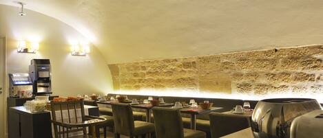 Ein Restaurant mit Stehwänden, Tischen, Stühlen und einer Kaffeemaschine.