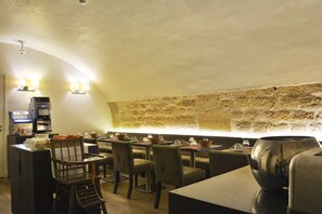 Un restaurant avec un mur en pierre, des tables, des chaises et un appareil à café.