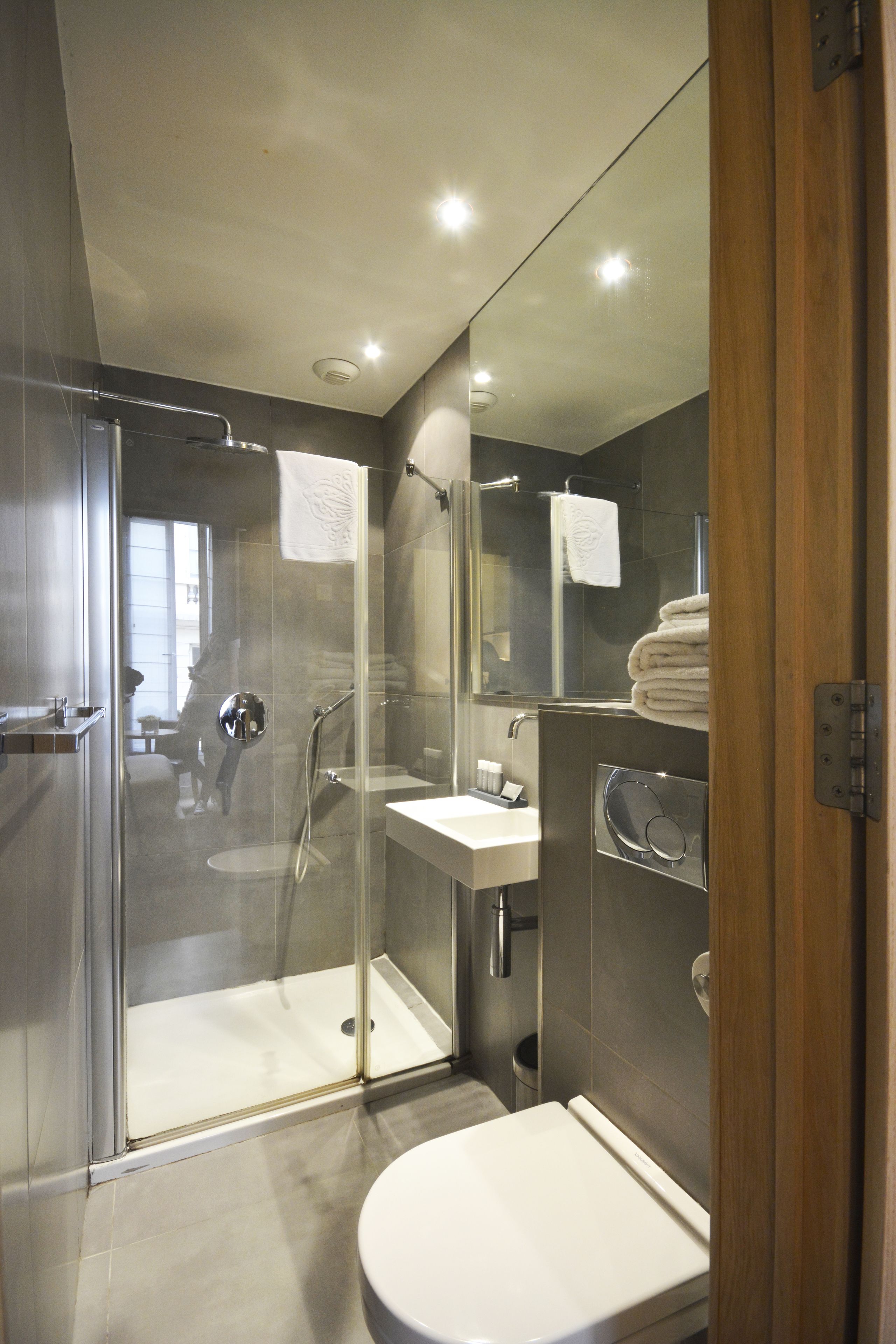 Un baño moderno con ducha acristalada, lavabo blanco y retrete.