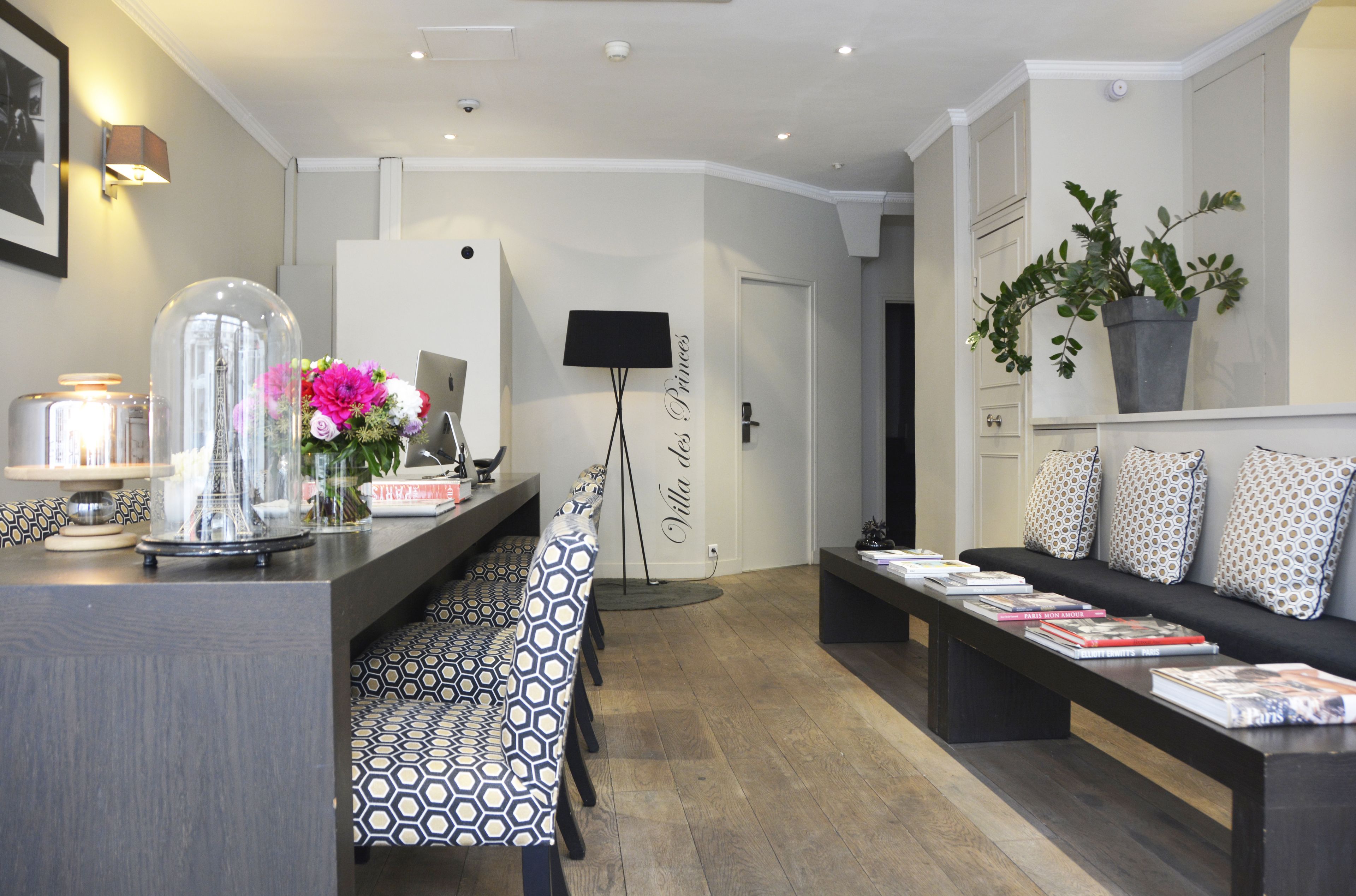 Una sala de estar moderna con sofá, una mesa de centro, una zona de comedor con mantel estampado y una cúpula de vidrio decorativa sobre un arreglo floral.