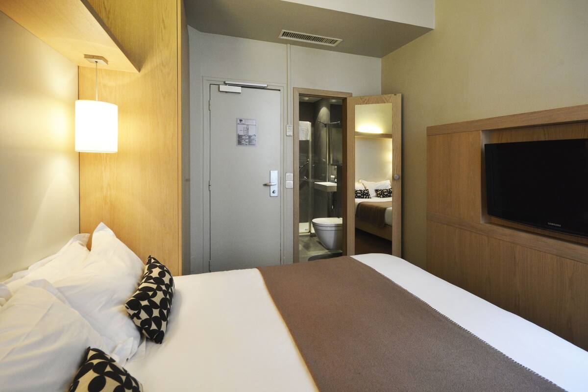 A hotel room with a bed, a television, a shower, and a toilet.