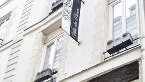 A hotel facade with a sign indicating it is a hotel, a visible entrance, and a window with a decorative design. - Villa Des Princes (Paris)