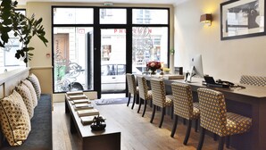 A hotel lobby with a reception desk, seating area, and a view of the street outside. - Villa Des Princes (Paris)