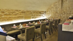 A restaurant with stone walls, long tables, and cushioned chairs. - Villa Des Princes (Paris)