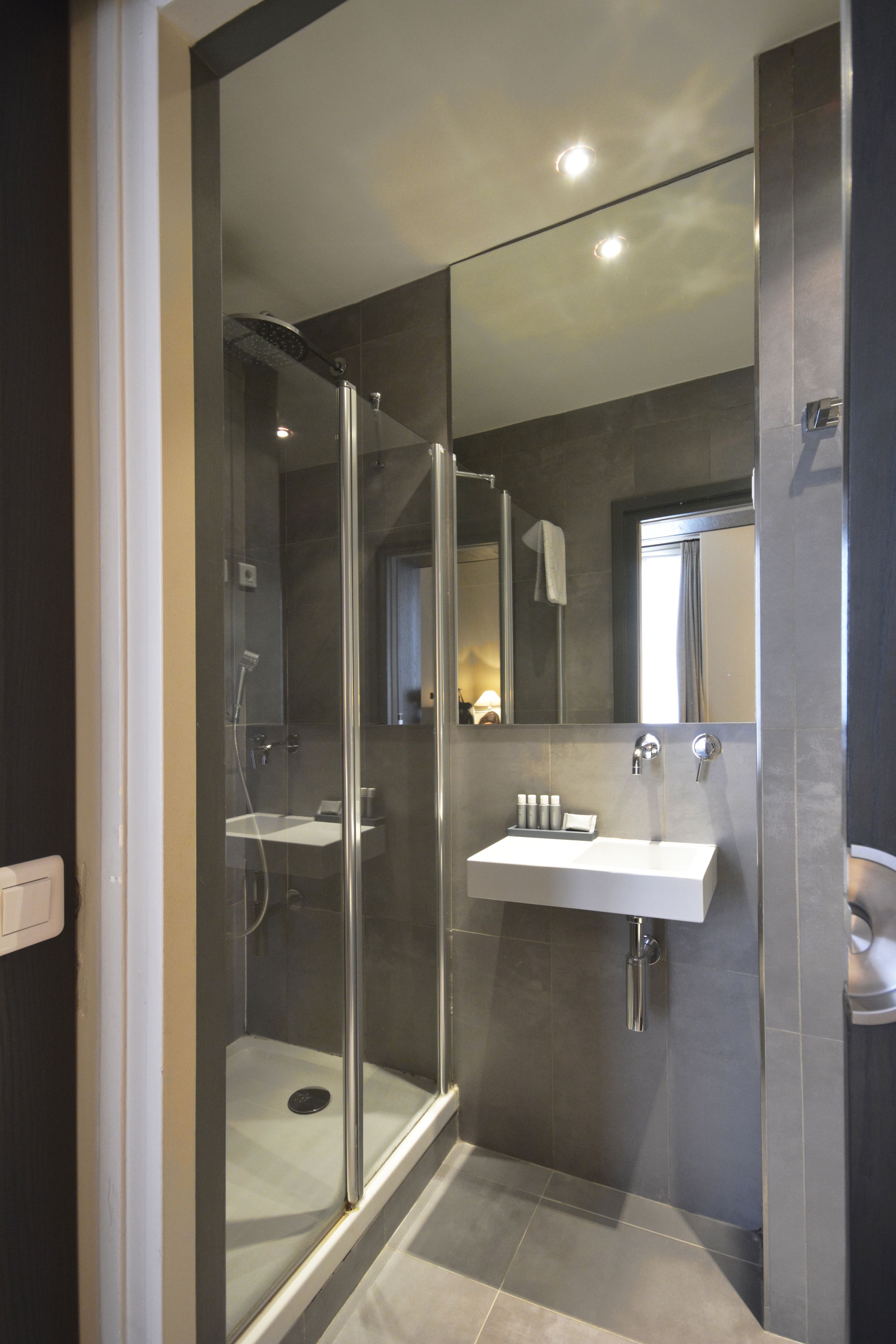 A modern bathroom with a glass-enclosed shower, a white sink, and a large mirror.