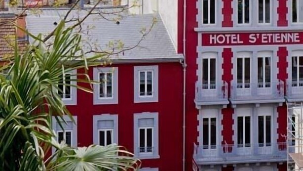 A building with a sign reading "HOTEL S'TIENNE" and a view of a castle in the background. - Hotel St-Etienne (Lourdes)