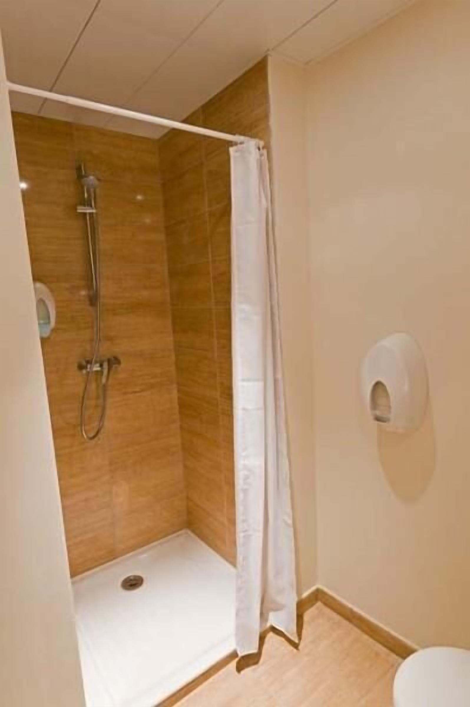 A small, modern bathroom with a shower, a toilet, and a hand dryer.
