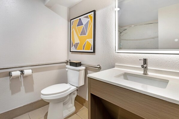 Un baño moderno con inodoro, lavamanos y una obra de arte abstracta enmarcada en la pared.