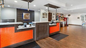 A reception area with a modern design, featuring a reception desk, a clock, and a wall-mounted logo. - Comfort Inn & Suites Sacramento - University Area (Sacramento)