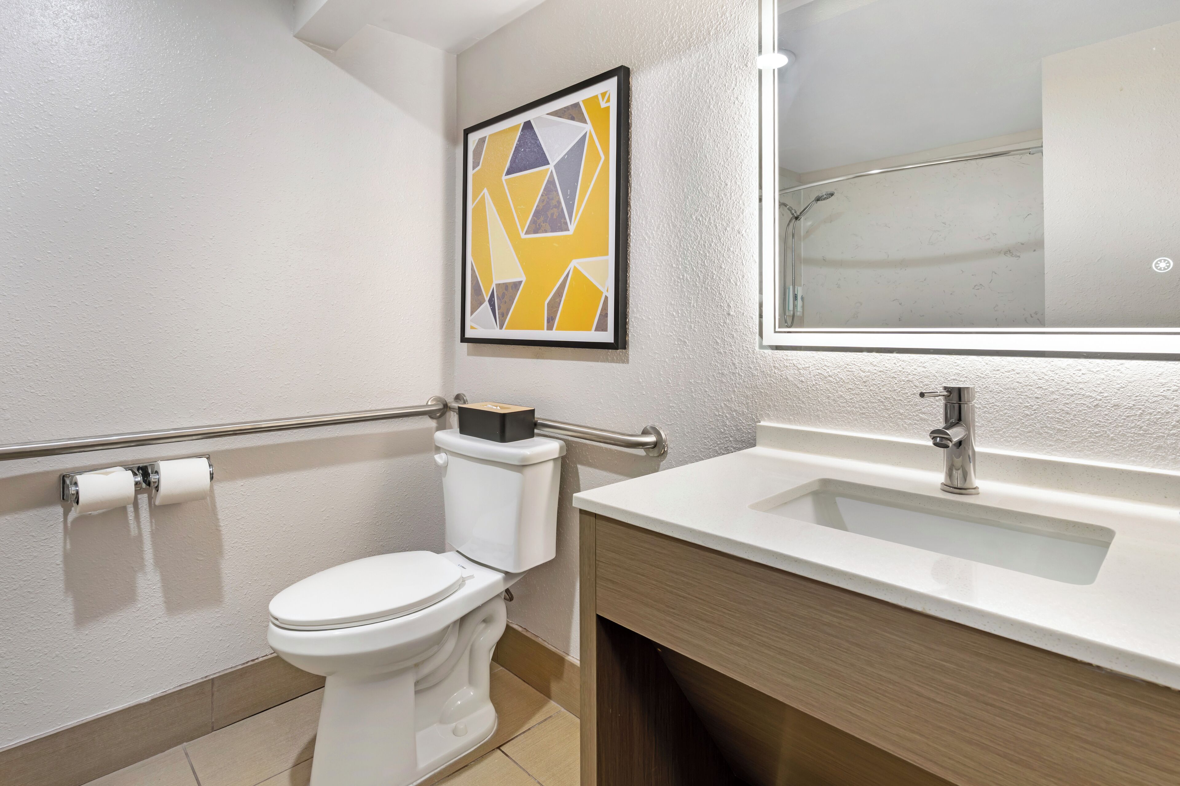 Ein modernes Badezimmer mit Toilette, Waschbecken und Handlauf.
