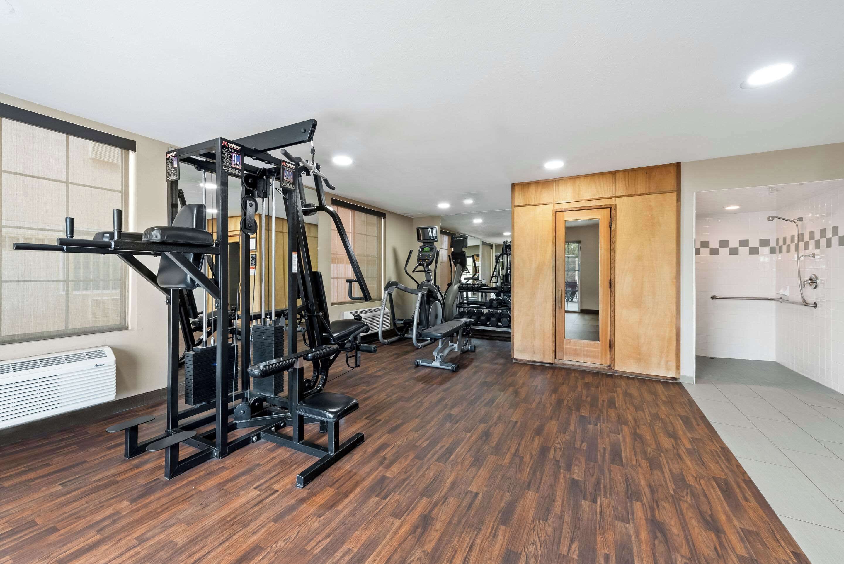 Une salle de sport équipée de matériel d’exercice, avec un miroir et une porte en bois.