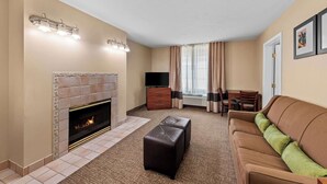 Quarto de hotel com lareira, sofá, televisão e área de jantar.