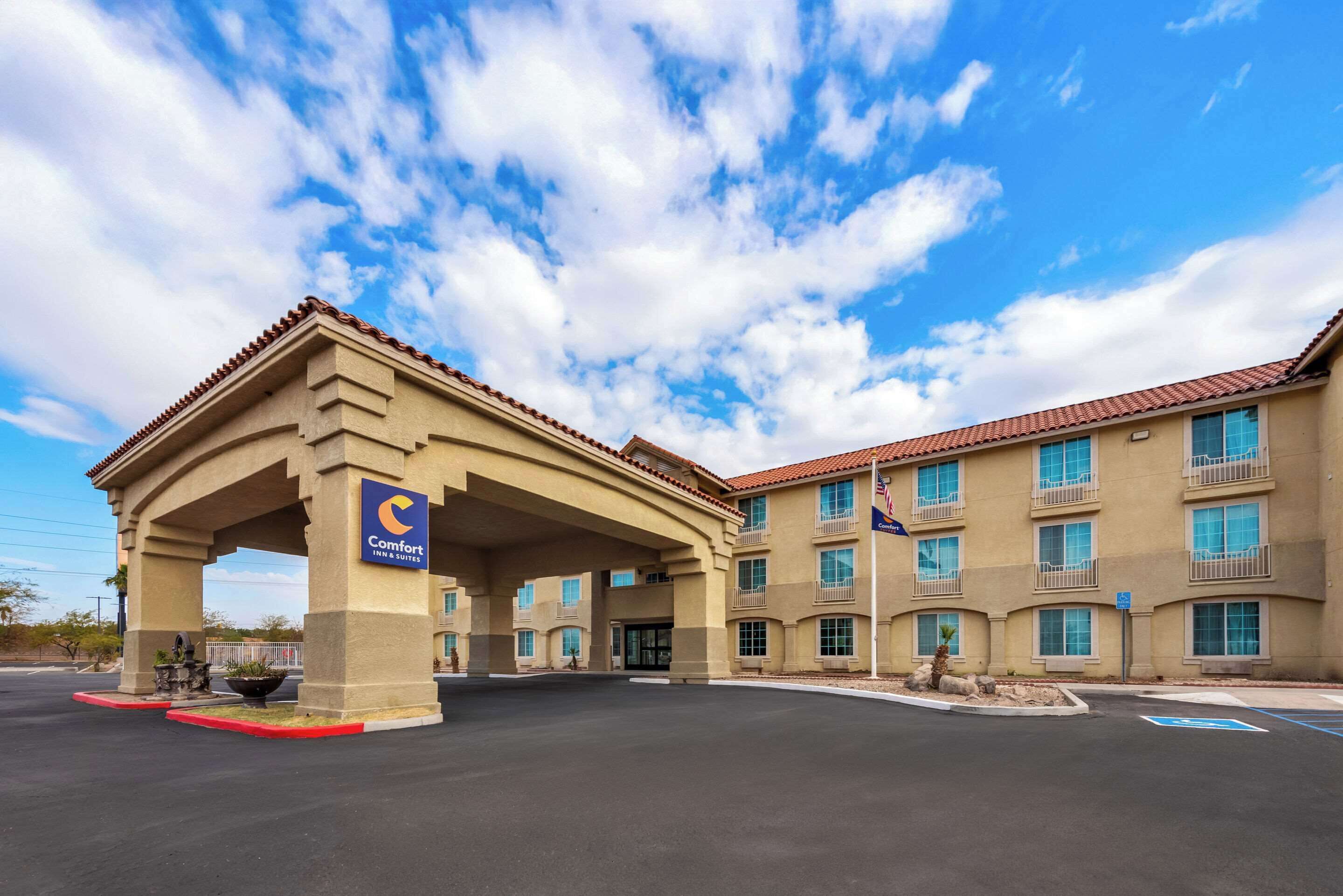A Comfort Inn & Suites hotel with a covered entrance, multiple balconies, and a clear sky.