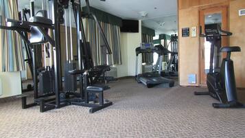 A gym with various exercise equipment including a treadmill, elliptical, and weight machines.