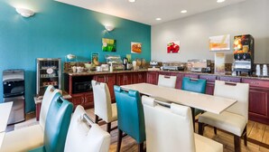 Un área de cocina moderna con una mesa de comedor y sillas, un refrigerador y una cafetera.