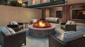 An outdoor seating area with wicker furniture and a central fire pit.