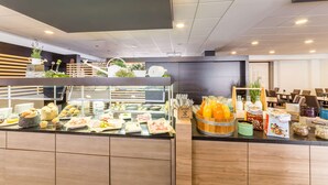 Un área de buffet con diversas opciones de comida, una barra de zumos y diferentes disposiciones de asientos.