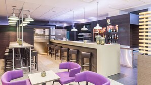 Un área de bar moderna con mostrador, asientos e iluminación colgante.