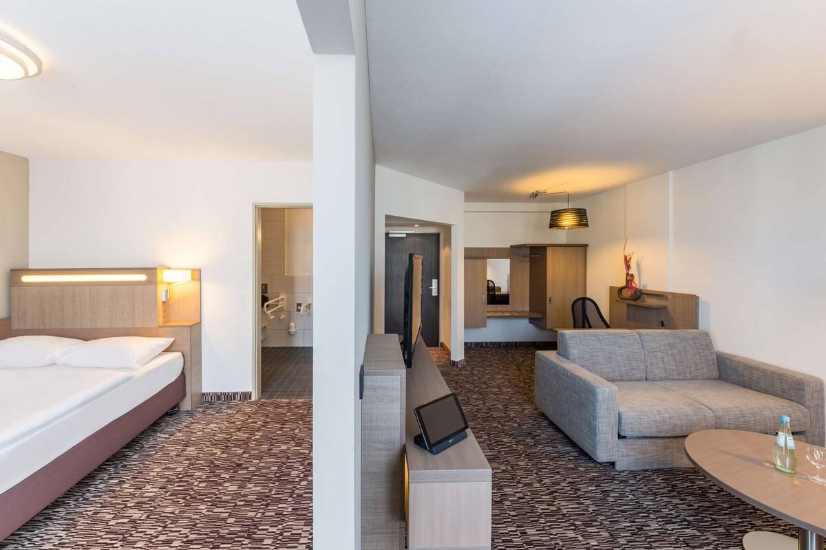 Ein Hotelzimmer mit Bett, Schreibtisch, Sofa und einem kleinen Tisch.