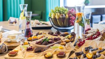 Een tafel met diverse desserts en fruit, waaronder een schaal druiven en een kan ijsthee.