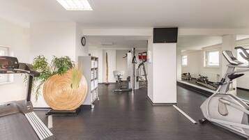 A gym with cardio machines, a large wooden sculpture, and a treadmill.