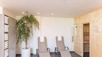 Relax in a serene space with a potted plant, lounge chairs, and a glass door leading to another area.
