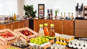 A breakfast buffet with various fruits, beverages, and food items. - NH Ingolstadt (Ingolstadt)