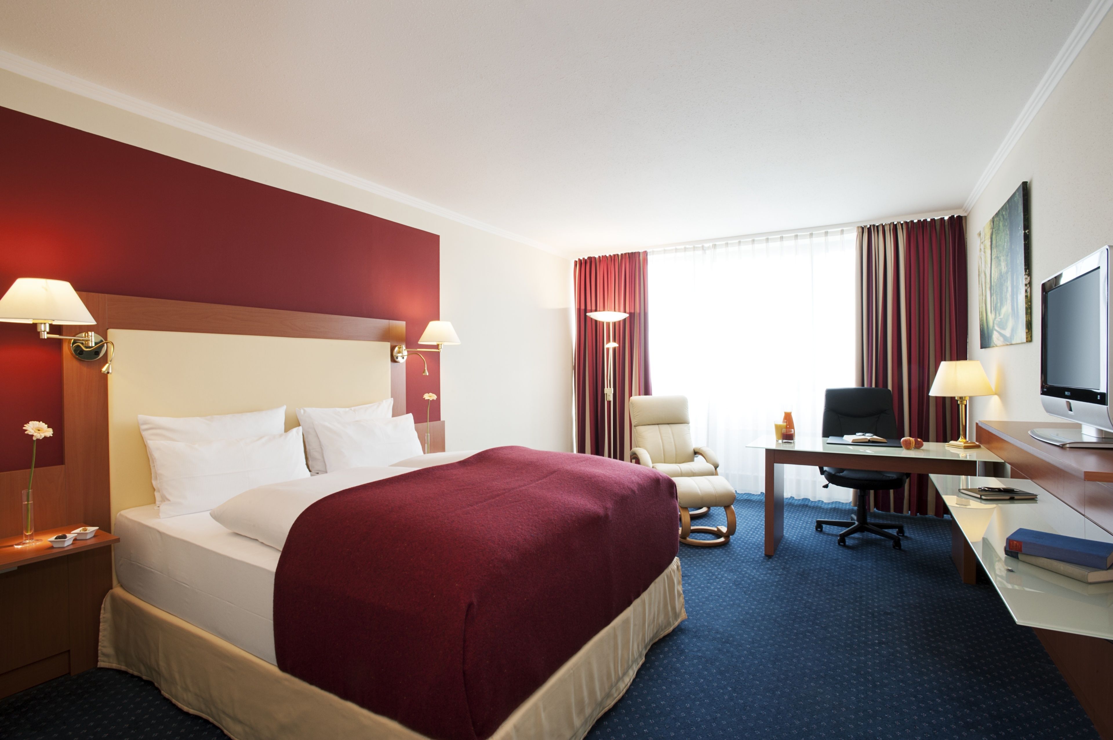 Een hotelkamer met een groot bed, een bureau met een computer, een stoel en een televisie.
