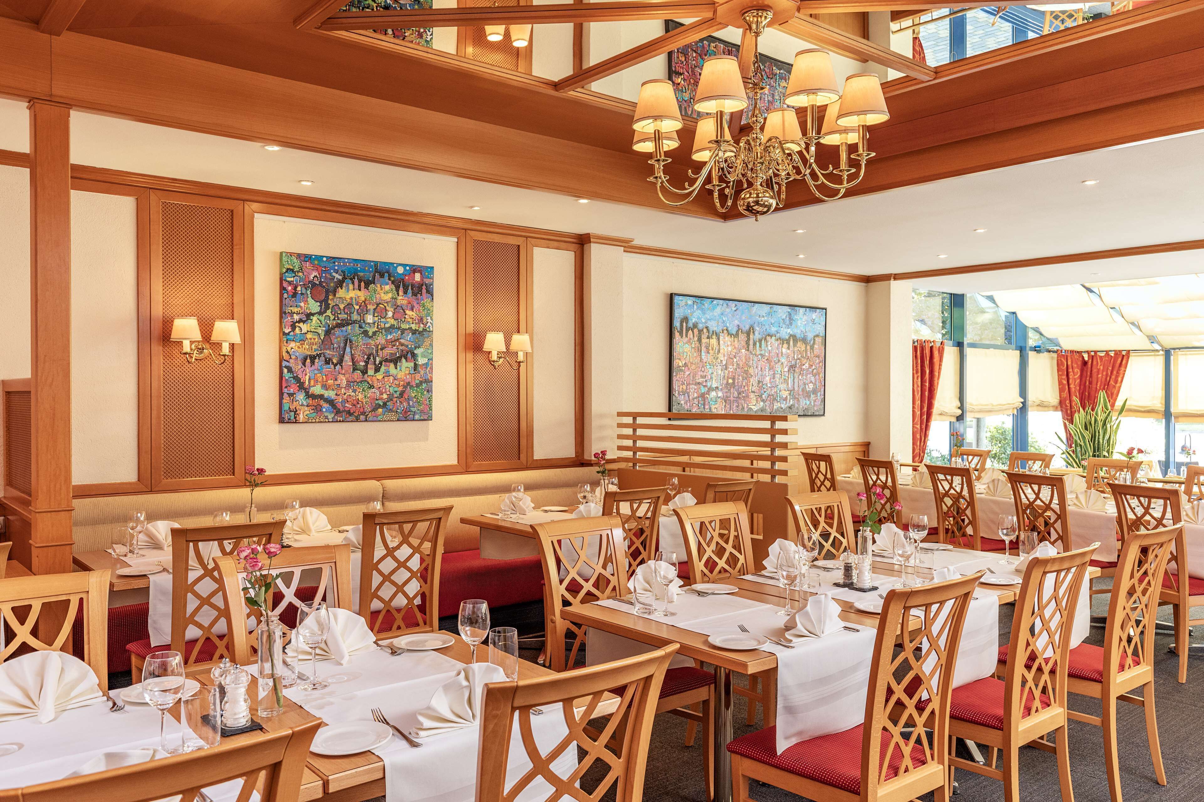 Un restaurant avec des meubles en bois, des nappes blanches et des lustres.